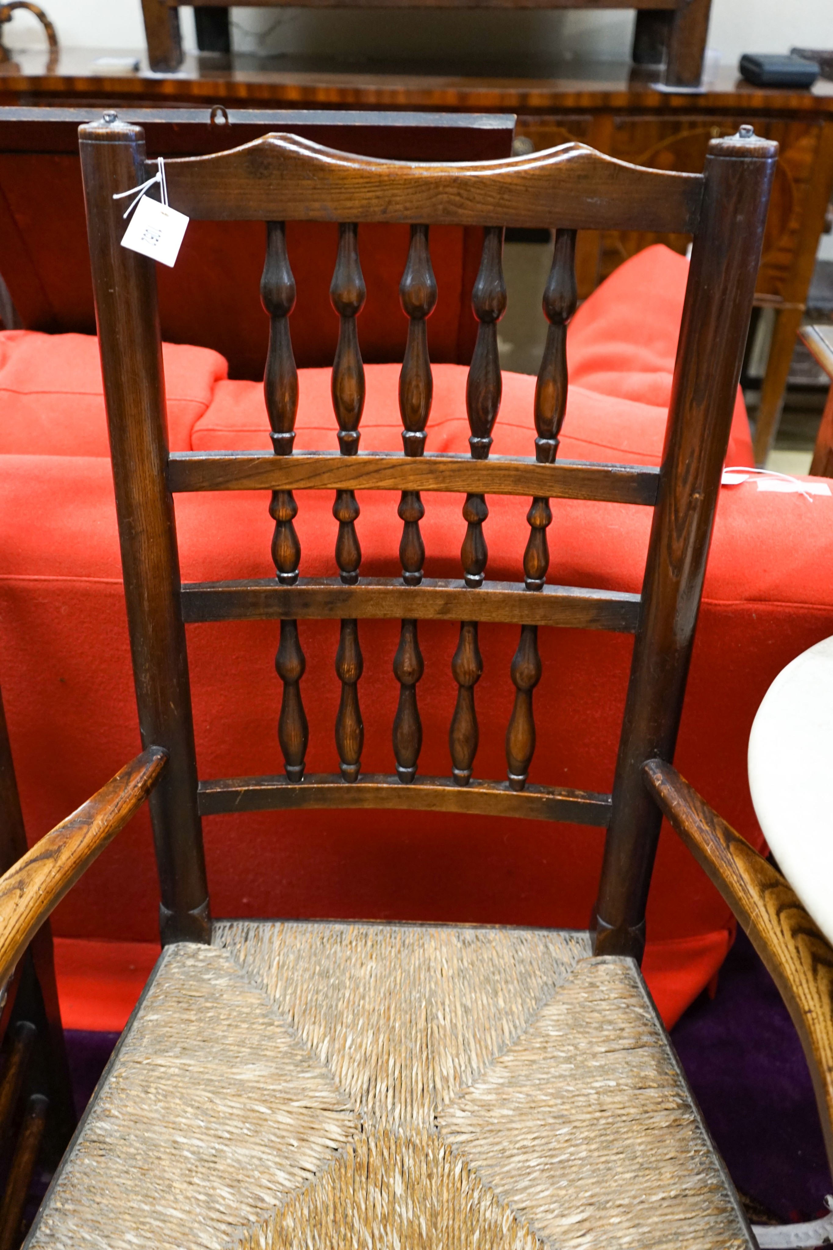 A near pair of Lancashire ash and elm rush seat spindle back elbow chairs